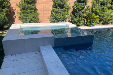 Idee per una piscina minimalista di medie dimensioni e dietro casa con pavimentazioni in cemento