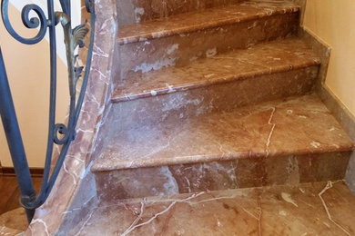 Foto de escalera curva clásica pequeña con escalones de mármol y contrahuellas de mármol