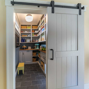 Inspiration pour une arrière-cuisine rustique de taille moyenne avec un placard avec porte à panneau encastré, des portes de placard grises, un plan de travail en bois, un sol en carrelage de céramique et un sol gris.