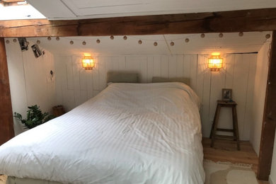 Cette photo montre une grande chambre parentale exotique en bois avec un mur blanc, parquet clair et un sol beige.