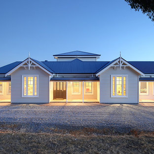 Expansive country one-storey white house exterior in Adelaide with vinyl siding, a gable roof and a metal roof.