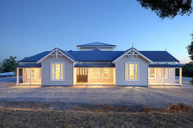 Expansive country one-storey white house exterior in Adelaide with vinyl siding, a gable roof and a metal roof.