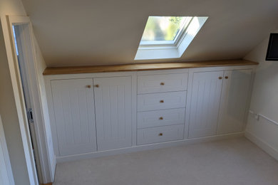 Modelo de dormitorio principal actual de tamaño medio con paredes blancas, moqueta y suelo beige