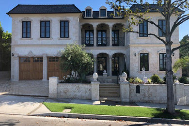 Example of a mid-sized arts and crafts beige two-story stone house exterior design in Orange County with a clipped gable roof and a tile roof