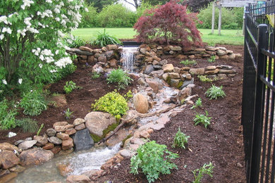 Photo of a large transitional backyard mulch water fountain landscape in Bridgeport.