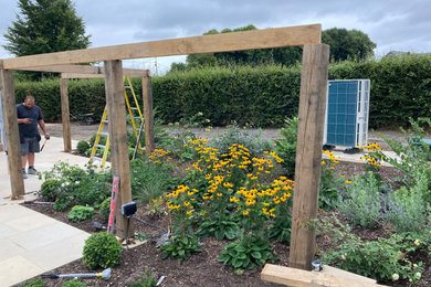 Photo of a medium sized contemporary back formal full sun garden for autumn in Dorset with a flowerbed and natural stone paving.
