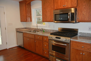 Example of a small single-wall medium tone wood floor eat-in kitchen design in Other with a double-bowl sink, flat-panel cabinets, laminate countertops, stainless steel appliances, a peninsula and medium tone wood cabinets