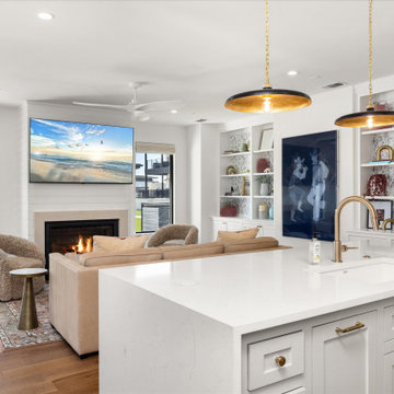 Open-concept kitchen and living area with a cozy fireplace, statement pendant li