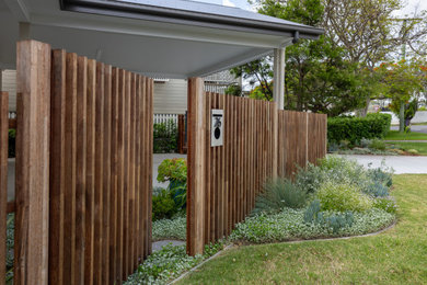 Inspiration for a mid-sized and australian native contemporary front yard full sun garden in Brisbane with a wood fence.