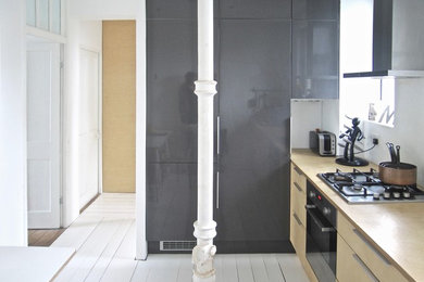 ロンドンにある低価格の小さなコンテンポラリースタイルのおしゃれなキッチン (ドロップインシンク、フラットパネル扉のキャビネット、淡色木目調キャビネット、木材カウンター、白いキッチンパネル、シルバーの調理設備、塗装フローリング、白い床) の写真