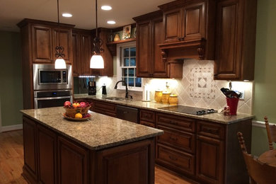 Eat-in kitchen - mid-sized traditional l-shaped medium tone wood floor eat-in kitchen idea in Atlanta with a double-bowl sink, raised-panel cabinets, dark wood cabinets, granite countertops, beige backsplash, stainless steel appliances and an island