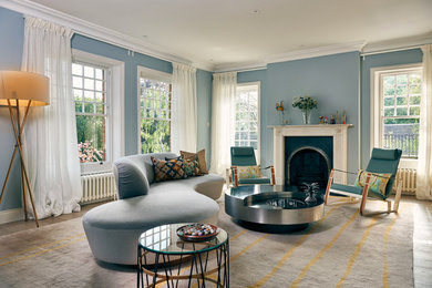 Design ideas for a contemporary living room in London with blue walls, medium hardwood flooring, a standard fireplace and brown floors.