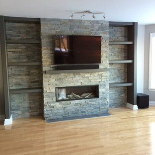 Inspiration for a mid-sized modern open concept family room in Ottawa with grey walls, light hardwood floors, a standard fireplace, a stone fireplace surround, a wall-mounted tv and brown floor.