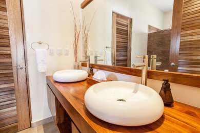 Mid-sized trendy ceramic tile and beige floor bathroom photo in San Diego with flat-panel cabinets, medium tone wood cabinets, white walls, a vessel sink and wood countertops