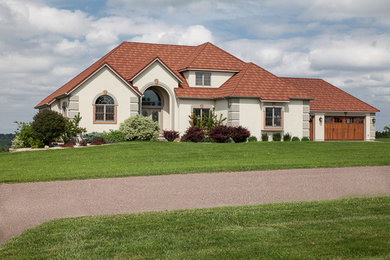 Large mediterranean beige two-story stucco house exterior idea in Other with a hip roof and a shingle roof