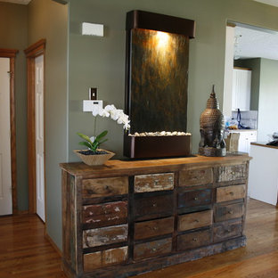 Idee per un piccolo soggiorno etnico aperto con libreria, pareti verdi e pavimento in legno massello medio