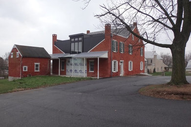 Inspiration for a large country red two-story brick exterior home remodel in Other with a mixed material roof