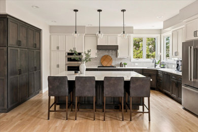 Open concept kitchen - large transitional u-shaped light wood floor and brown floor open concept kitchen idea in Denver with an undermount sink, shaker cabinets, granite countertops, beige backsplash, porcelain backsplash, stainless steel appliances, an island and white countertops