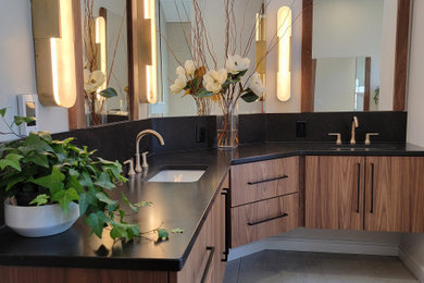 Example of a mid-sized minimalist master beige floor and double-sink bathroom design in Burlington with flat-panel cabinets, medium tone wood cabinets, an undermount sink, quartz countertops and black countertops