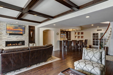 Large walk-out laminate floor, brown floor and coffered ceiling basement photo in Grand Rapids with a home theater, white walls, a standard fireplace and a stone fireplace