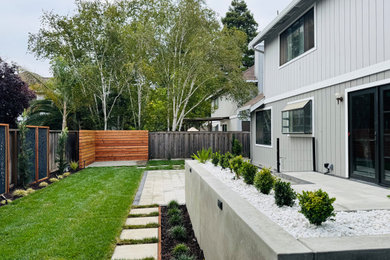 Photo of a mid-sized modern full sun backyard brick and metal fence retaining wall landscape in San Francisco.