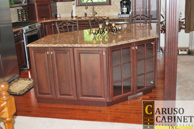 Example of a small classic l-shaped medium tone wood floor eat-in kitchen design in Other with a double-bowl sink, raised-panel cabinets, dark wood cabinets, quartzite countertops, beige backsplash, ceramic backsplash, stainless steel appliances and an island