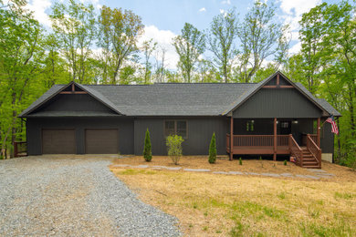 Inspiration for a rustic black two-story board and batten and vinyl exterior home remodel in Charlotte with a shingle roof and a black roof
