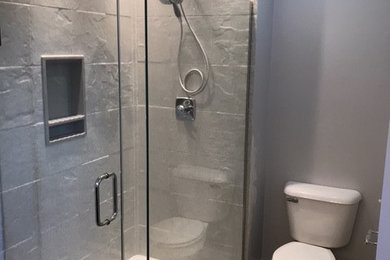 Medium sized traditional ensuite bathroom in Columbus with beaded cabinets, white cabinets, a freestanding bath, a corner shower, a two-piece toilet, grey tiles, grey walls, vinyl flooring, a submerged sink, engineered stone worktops, multi-coloured floors, a hinged door and white worktops.