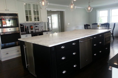 Inspiration for a large transitional galley dark wood floor open concept kitchen remodel in New York with a farmhouse sink, shaker cabinets, white cabinets, marble countertops, gray backsplash, subway tile backsplash, stainless steel appliances and an island