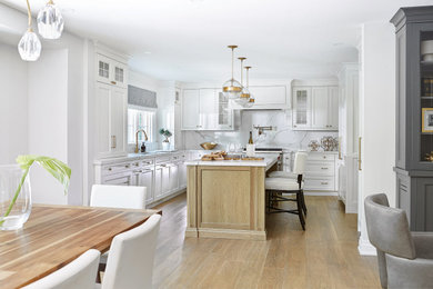 Example of a large transitional u-shaped light wood floor open concept kitchen design in Toronto with an undermount sink, recessed-panel cabinets, white cabinets, white backsplash, an island and white countertops