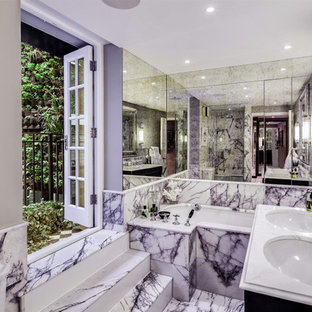 Diseño de cuarto de baño principal, clásico, de tamaño medio, con armarios con rebordes decorativos, puertas de armario negras, bañera encastrada, sanitario de una pieza, baldosas y/o azulejos multicolor, baldosas y/o azulejos con efecto espejo, paredes grises, suelo de mármol, lavabo tipo consola, encimera de mármol, suelo multicolor y encimeras blancas