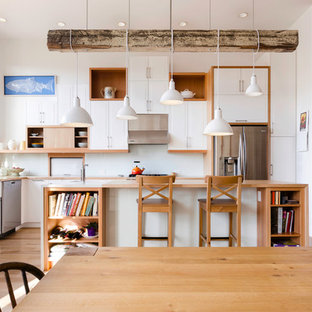 Immagine di una cucina minimal con lavello stile country, ante in stile shaker, ante bianche, top in legno, paraspruzzi bianco, paraspruzzi con lastra di vetro e elettrodomestici in acciaio inossidabile