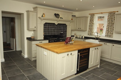 Photo of a large contemporary u-shaped enclosed kitchen in Other with a belfast sink, beaded cabinets, grey cabinets, granite worktops, integrated appliances, slate flooring and an island.