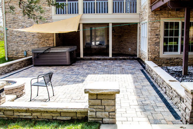 This is an example of a mid-sized backyard patio in Cincinnati with a fire feature, natural stone pavers and no cover.