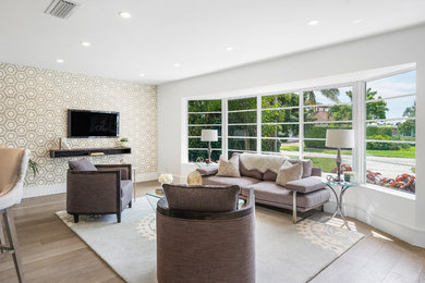 Small minimalist open concept medium tone wood floor and brown floor living room photo in Miami with gray walls and a wall-mounted tv
