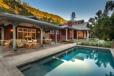 Example of a mid-sized cottage backyard concrete and rectangular lap pool design in Other