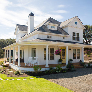 Bild på ett mellanstort lantligt vitt hus, med två våningar, valmat tak och tak i shingel