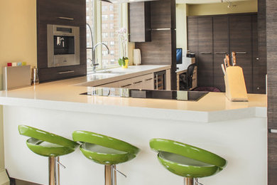 Inspiration for a mid-sized contemporary l-shaped light wood floor enclosed kitchen remodel in Calgary with a double-bowl sink, flat-panel cabinets, white cabinets, solid surface countertops, stainless steel appliances and a peninsula