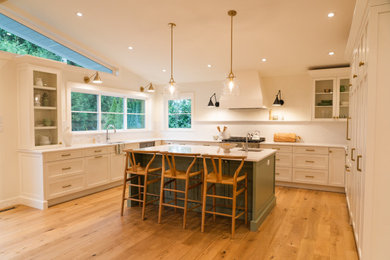 Example of a large transitional u-shaped light wood floor and vaulted ceiling eat-in kitchen design in Vancouver with an undermount sink, recessed-panel cabinets, quartzite countertops, white backsplash, quartz backsplash, stainless steel appliances, an island and white countertops