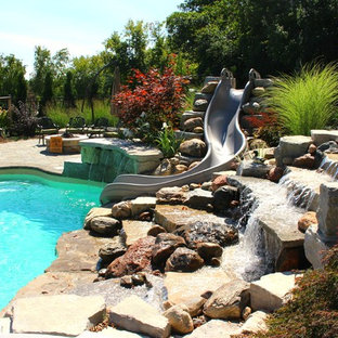 Idéer för en stor modern baddamm på baksidan av huset, med vattenrutschkana och marksten i tegel