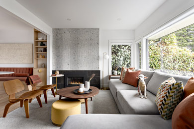 Example of a mid-sized 1950s open concept brown floor and light wood floor living room design in Vancouver with white walls, a standard fireplace and a tile fireplace
