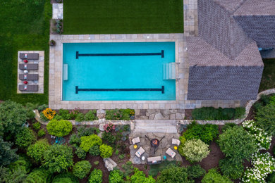 Design ideas for a large transitional backyard rectangular lap pool in Boston with a pool house and natural stone pavers.