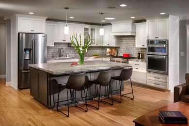 Example of a mid-sized transitional l-shaped light wood floor and brown floor open concept kitchen design in Sacramento with an undermount sink, shaker cabinets, white cabinets, marble countertops, gray backsplash, subway tile backsplash, stainless steel appliances, an island and gray countertops