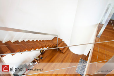 Cette image montre un escalier traditionnel en L avec des marches en bois et un garde-corps en métal.