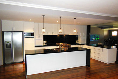 Design ideas for a mid-sized contemporary l-shaped open plan kitchen in Perth with a double-bowl sink, flat-panel cabinets, white cabinets, granite benchtops, black splashback, glass sheet splashback, stainless steel appliances, medium hardwood floors and with island.
