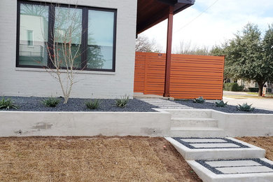 Photo of a mid-sized modern front yard partial sun xeriscape in Dallas with gravel.