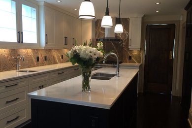 Inspiration for a large timeless l-shaped dark wood floor enclosed kitchen remodel in Toronto with a double-bowl sink, shaker cabinets, white cabinets, marble countertops, metallic backsplash, stone slab backsplash, stainless steel appliances and an island