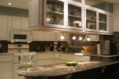 Kitchen - large traditional galley ceramic tile kitchen idea in Tampa with a drop-in sink, flat-panel cabinets, white cabinets, granite countertops, white backsplash, stainless steel appliances and an island