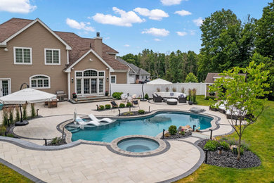Photo of a large modern backyard custom-shaped natural pool in Bridgeport with a hot tub and concrete pavers.