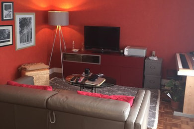 Réalisation d'un salon tradition de taille moyenne et fermé avec un mur rouge, un sol en bois brun, aucune cheminée et un téléviseur indépendant.